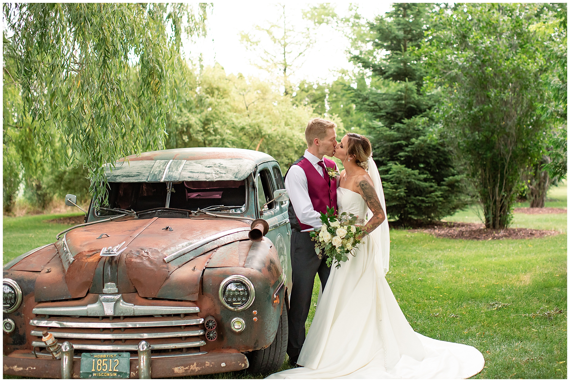 bride and groom kissing next to vintage car 