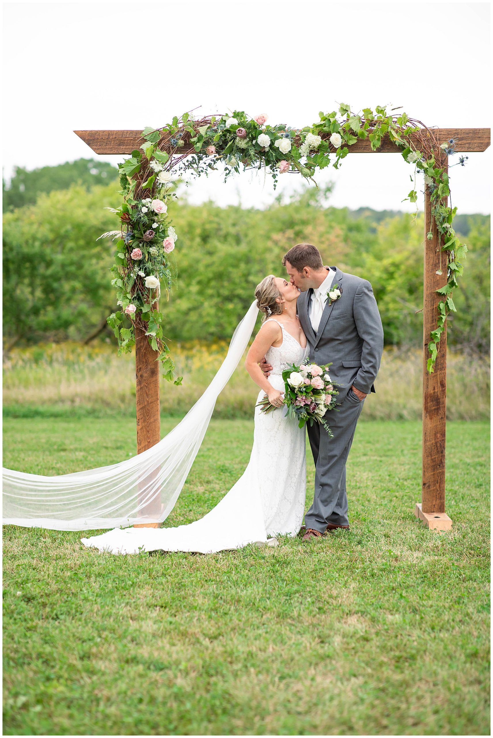 kissing under wedding arbor 