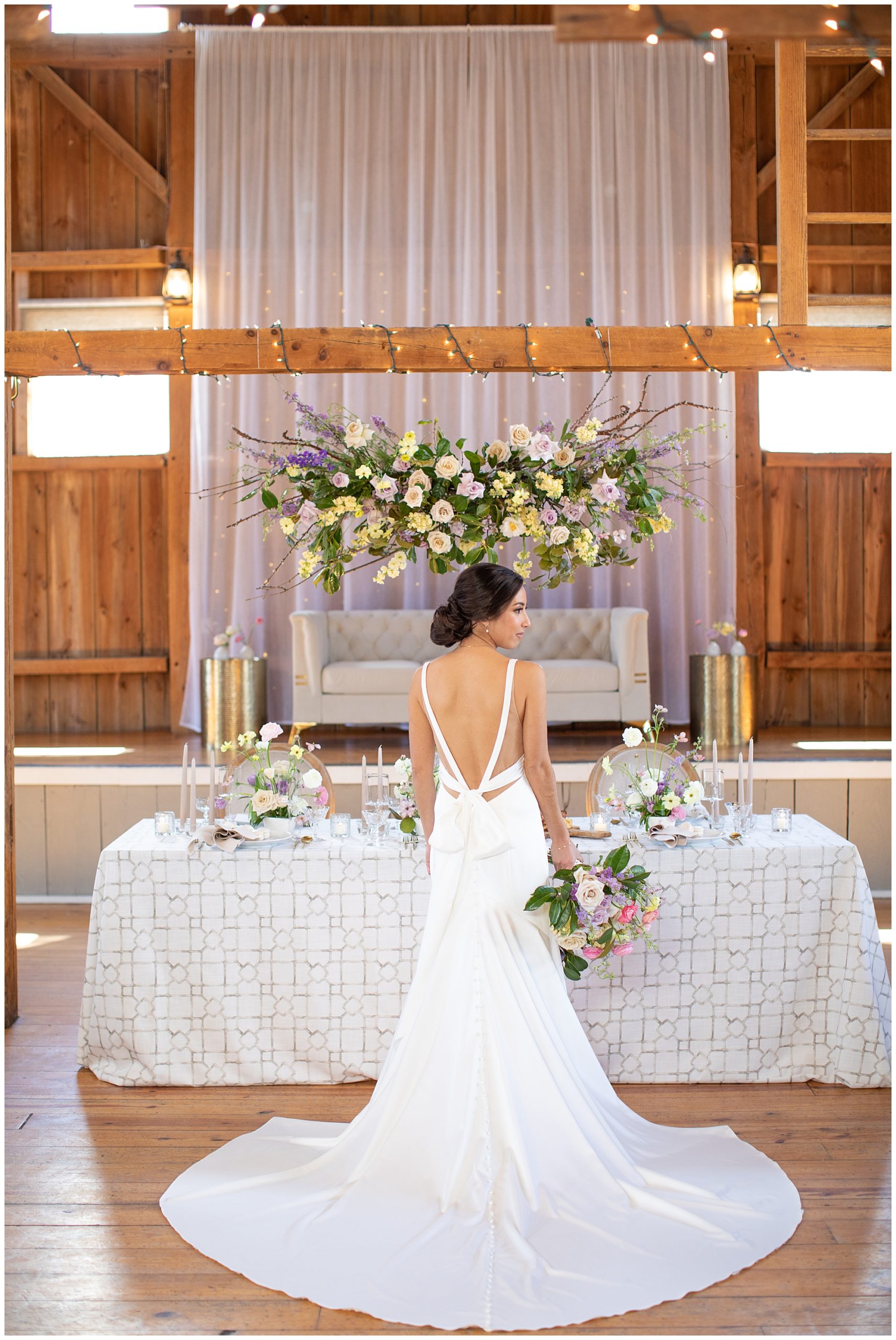 bride modeling in front of spring tablescape at Harvest Moon Pond with hanging floral install by Sunborn Gardens