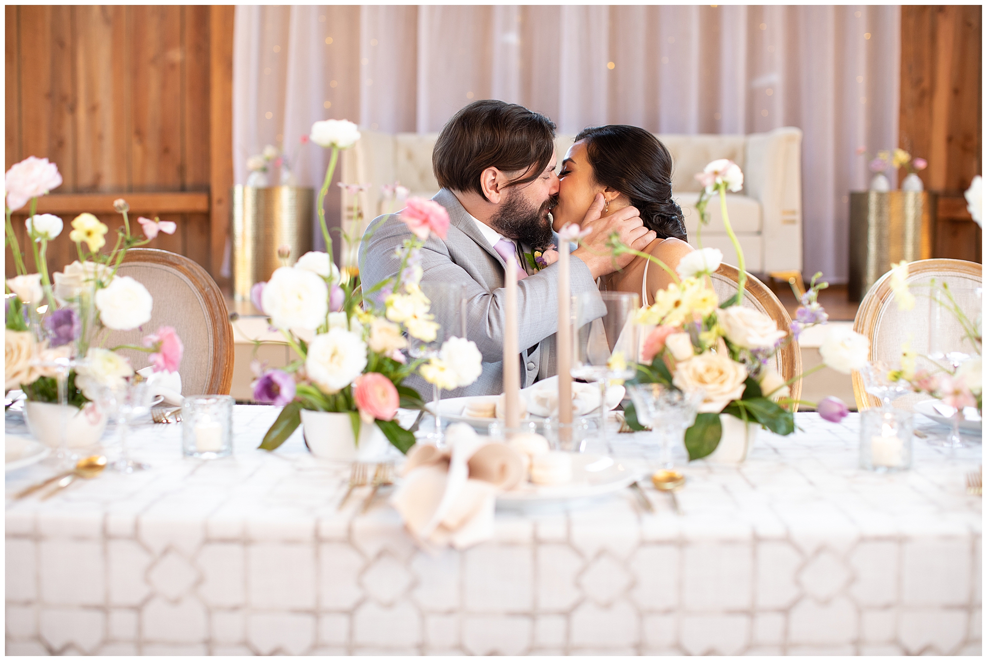 first kiss shot at wedding head table, spring florals on linen table cloth