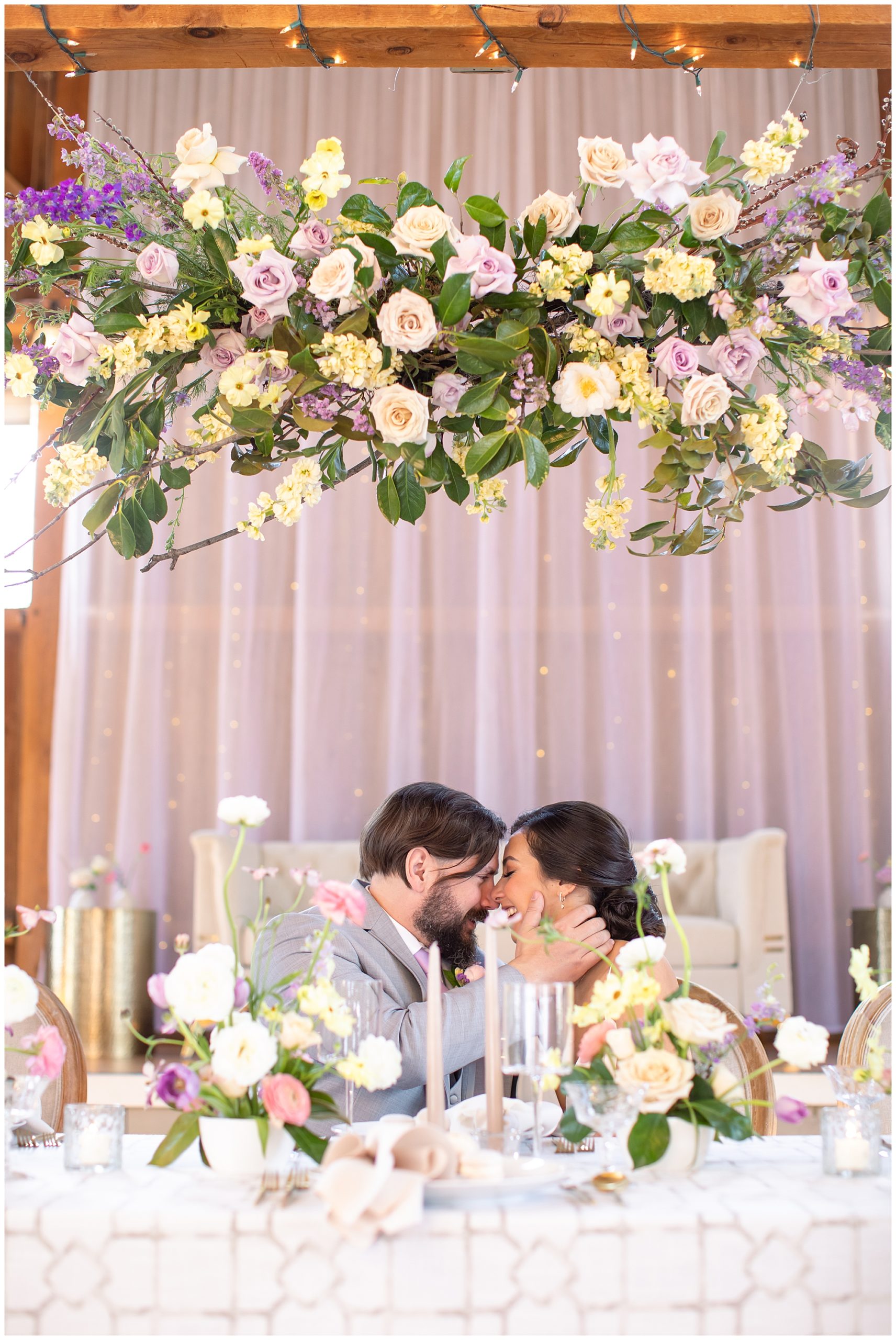 intimate kiss at head-table with floral installation and spring colors 